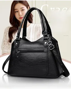 Detail of black pebbled leather tote bag with silver zipper and adjustable strap