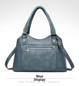 Detail of dark blue washed leather tote bag showing soft pebble texture and metal zipper