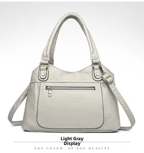 Detailed front view of light gray PU leather handbag with zipper pocket and silver hardware