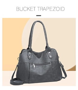 Détail du sac trapèze gris montrant la texture cuir grainé et les rivets argentés