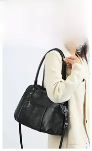 Close-up of black glossy leather handbag styled with a beige suit for side shoulder carry