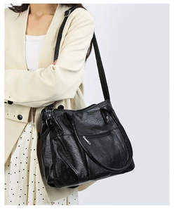 Detailed view of a soft black leather tote bag with subtle wrinkles and circular handles