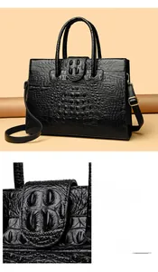 Detail of black crocodile texture tote bag with reinforced handles and adjustable strap