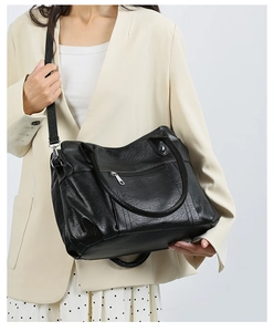 Détail d'un sac bandoulière en cuir souple noir avec texture plissée et fermeture éclair argent