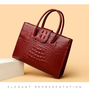 Detail showing deep red crocodile pattern texture and sturdy handles of this tote bag