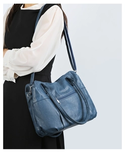 Detail view of large blue vintage tote bag showing soft leather texture and side pocket