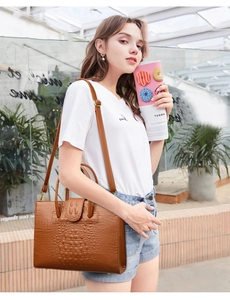 Detail shot of brown crocodile embossed leather texture on women's tote bag