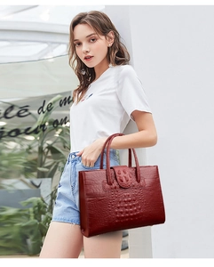 Detail of burgundy crocodile-embossed tote bag with elegant texture and sturdy handles