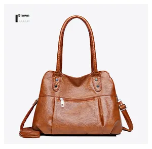 Detail view of brown soft leather tote bag with decorative zippers and metal buckles