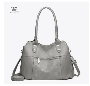 Détail d'un cabas en cuir souple gris clair avec bandoulières et poche zippée