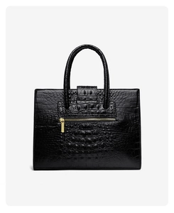 Detail of black crocodile embossed leather handbag with golden front zipper pocket