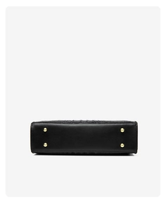 Close-up of black crocodile embossed tote bag base featuring four golden metal feet