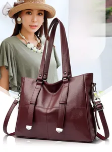 Détails macro du sac cabas en cuir bordeaux avec finitions métalliques argentées élégantes