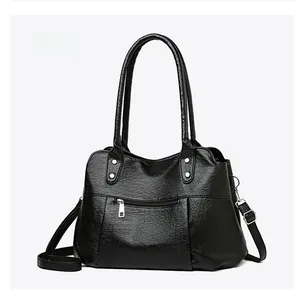 Détail de la texture cuir grainé noir sur le sac à main avec rivets argentés et zips