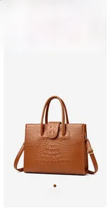 Detail of yellow-brown tote bag with faux crocodile skin texture and sturdy top handles