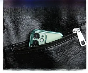Détail d'un sac cabas noir avec poche zippée avant et smartphone pour la capacité