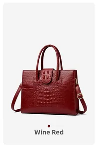 Detail of wine red tote bag with crocodile texture and gold hardware accents