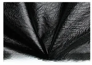 Gros plan sur le cuir grainé noir montrant la texture premium et les plis naturels du sac