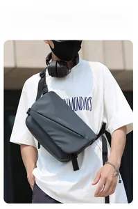 Waterproof dark grey messenger bag for men with adjustable strap shown on model outdoors