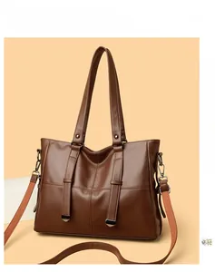 Détail d'un sac cabas marron montrant la texture du cuir et la bandoulière réglable