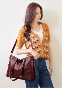 Sac fourre-tout tendance en cuir bordeaux porté par un mannequin avec bandoulière réglable