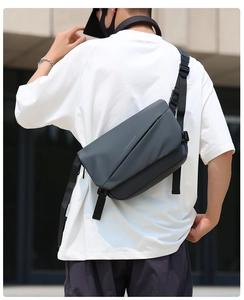 Rear view of model wearing a dark gray waterproof crossbody bag with white typography