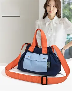 Detail of color-block nylon crossbody bag with contrast handles and adjustable strap