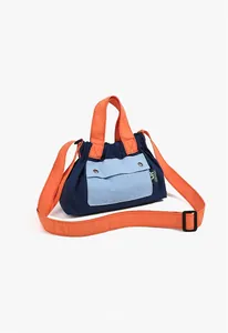Detail view of a color-block nylon crossbody bag with contrast orange straps and metal snaps