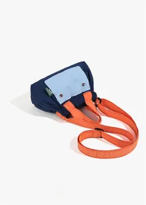 Detail of color-block nylon crossbody bag showing navy body and orange handles