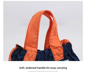Detail of soft widened orange handle with fine stitching on a contrast nylon bag