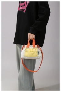 Close-up of lightweight nylon crossbody bag with orange handles and yellow front pocket