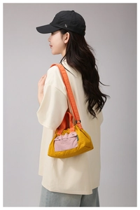 Detailed side view of nylon crossbody bag with mustard yellow body and orange handle