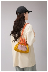 Detail of a bright yellow nylon crossbody bag with contrast pink pocket and orange straps