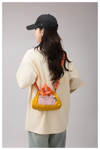 Detail of color-block nylon crossbody bag with mustard yellow and orange panels on model