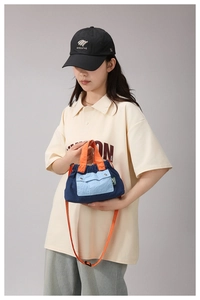 Detail of a nylon crossbody bag in navy and orange being carried by a model outdoors