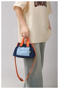 Detail of blue nylon crossbody bag with orange handle and drawstring closure
