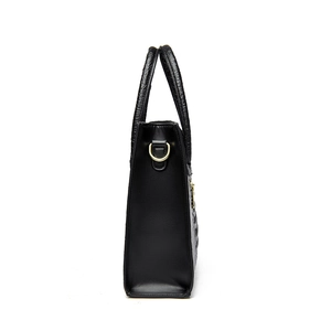 Modern black crocodile pattern tote bag with gold hardware shown from a side profile view