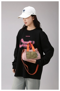 Detail of pink nylon crossbody bag with orange handle and olive green snap pocket