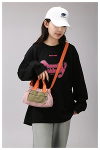 Close-up of pink nylon crossbody bag with orange handles and utility pocket detail