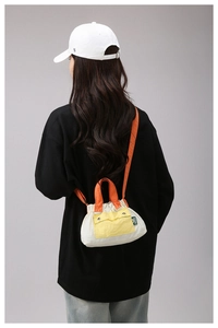 Detail of a color-block nylon crossbody bag featuring yellow flap and orange handles