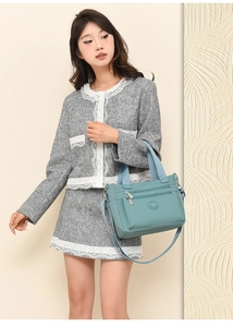 Detail of light blue nylon tote bag showing multiple zipper pockets and shoulder strap