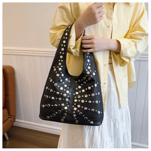 Detail einer schwarzen Gothic-Tasche mit Nieten, getragen von einem Model im Alltag