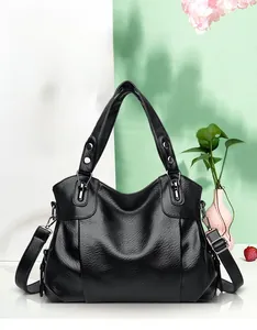 Detail of black pebbled leather texture on a large tote bag with silver metal buckles