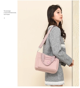 Pink nylon tote bag shown in use with multi-layer zipper pockets and wide shoulder strap