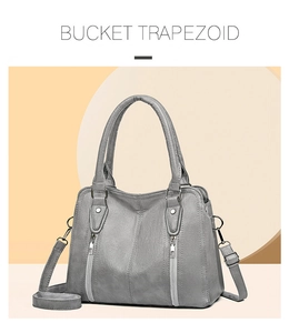 Detail view of grey trapezoid bucket bag with dual zippers and adjustable shoulder strap