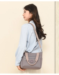 Detail of a lavender multi-pocket nylon shoulder bag with adjustable brown strap on a model