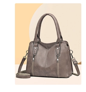 Detailed view of coffee brown faux leather handbag with silver zippers and double handles