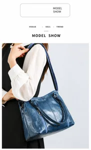 Blue glossy leather shoulder bag shown on model with dual zipper and metal hardware