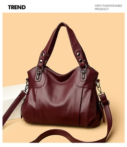 Detailed view of the dark red leather handbag with metallic studs and wide handle