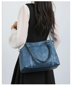 Detailed side view of blue leather tote bag with vertical zippers on a model